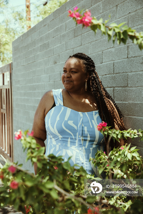 Plus size afro latinx Haitian American woman stands against wall looking away