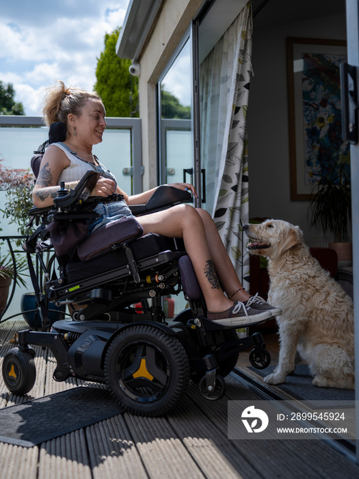 Woman in electric wheelchair relaxing on deck with dog