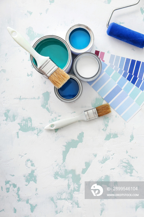 Cans of paint with supplies and palette samples on light background