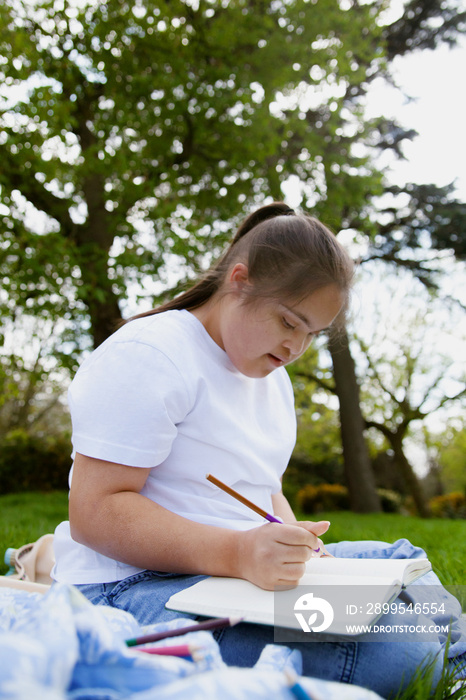 Young mid-sized woman with Down Syndrome writing in journal