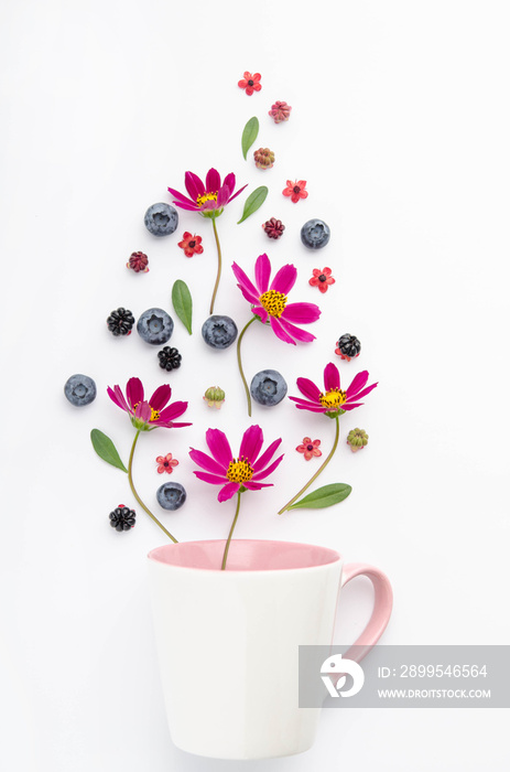 Composition of berries and flowers over a cup.