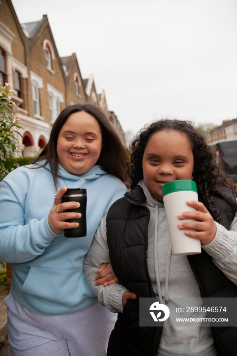 Two happy plus-sized women with Down Syndrome holding reusable coffee-to-go cups