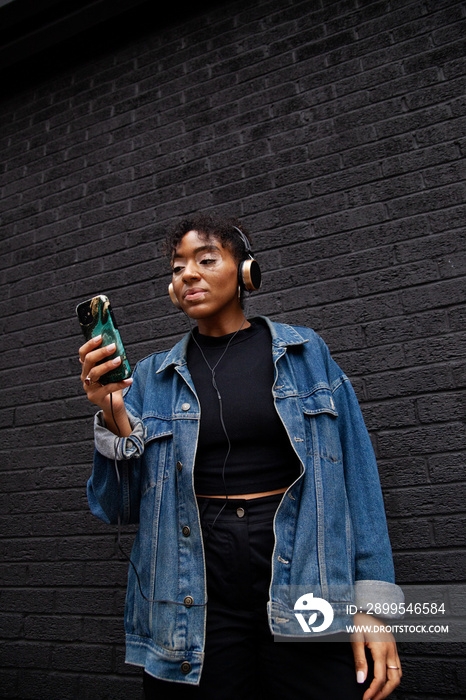 Curvy mixed-race woman with vitiligo taking a selfie in front of a black wall