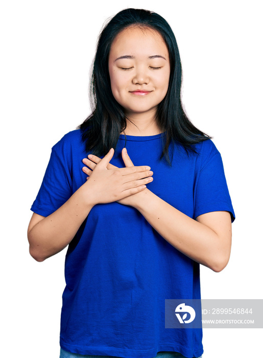 Young chinese woman wearing casual blue t shirt smiling with hands on chest, eyes closed with grateful gesture on face. health concept.