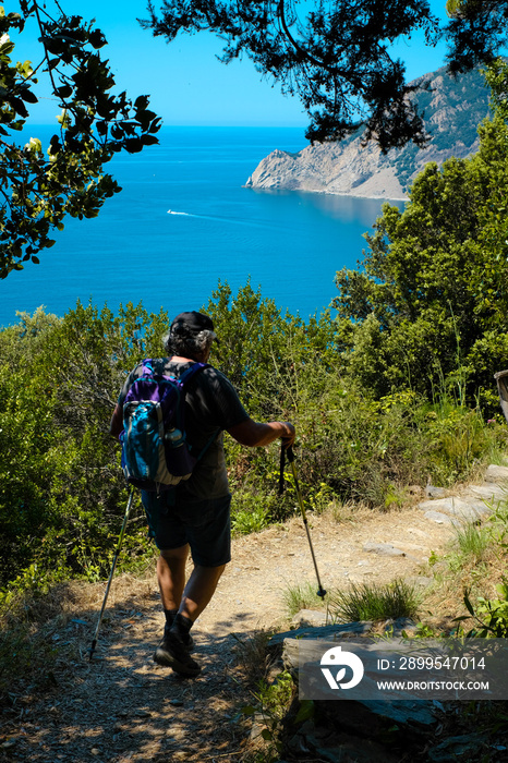 Persona adula sul sentiero azzurro delle cinque terre, monte rosso sul mare. concetto di vacanze in Liguria