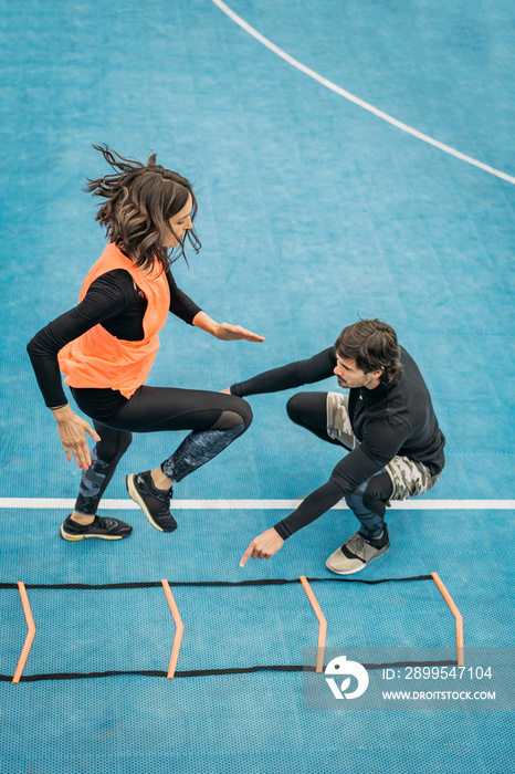 Young Woman Exercise using Agility Ladder, working with Fitness Coach