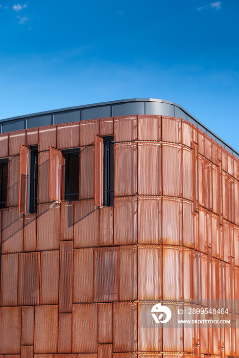 Rusted steel expanded metal mesh panels forming a modern building facade with deep blue sky in the background