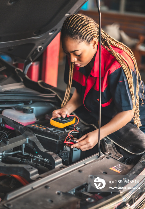 Auto service, repair, maintenance concept. Mechanic checks the car at the service station.African american woman  and asian engineer use tablet check car battery .