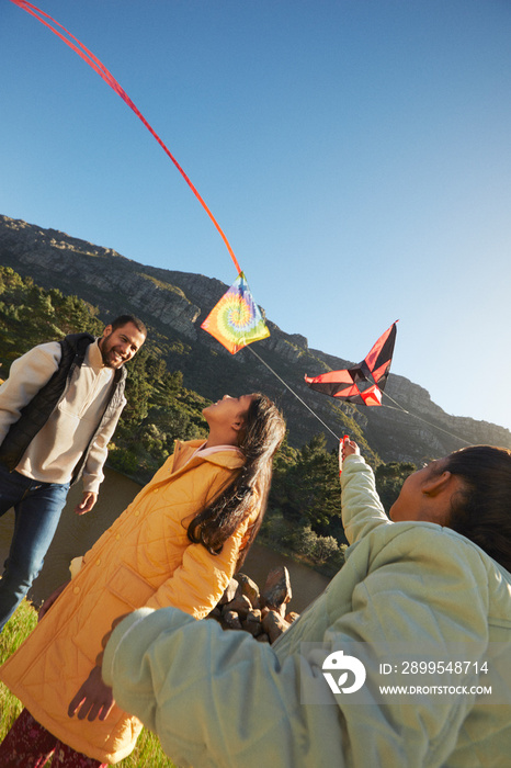 Father and little girls  flying kites during family camping trip with mountain backdrop and blue sky