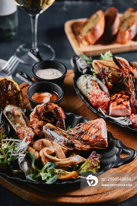 Assorted seafood on plates. Beautiful composition on a served seafood table, squid, shrimp, salmon steak and octopus. Food photo, low key, traditional Italian cuisine. Top view, save the space