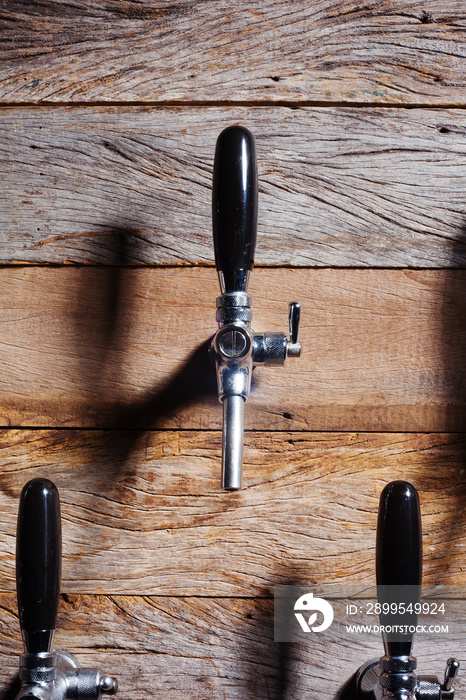 The beer taps in a pub. Alcohol concept. Vintage style. Beer craft over wooden background. Lights and shadows.