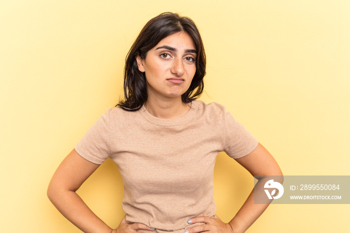 Young Indian woman isolated on yellow background sad, serious face, feeling miserable and displeased.