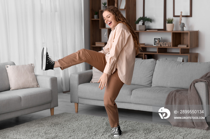 Young woman in earphones dancing at home