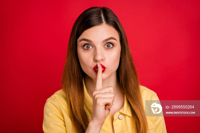 Closeup photo of attractive lady hold finger on lips say secret best friend chatterbox person sly eyes wear casual yellow blazer jacket isolated vibrant red color background