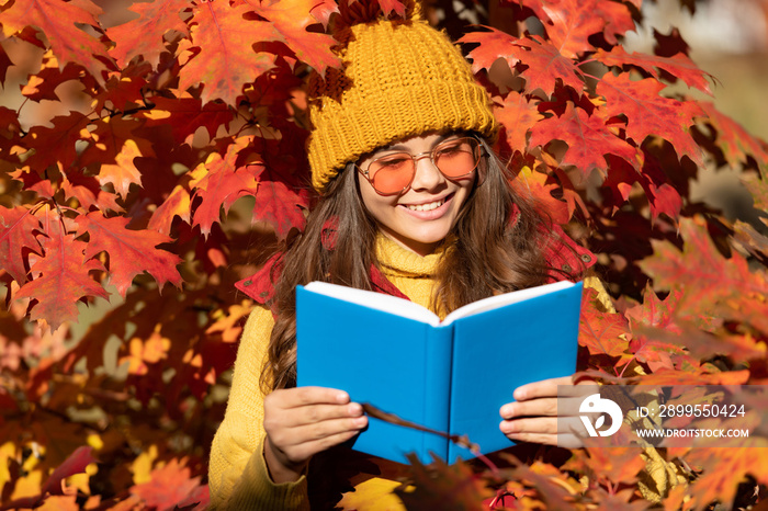 Autumn teenager girl portrait in fall autumn leaves. smiling child hold book on autumn leaves background
