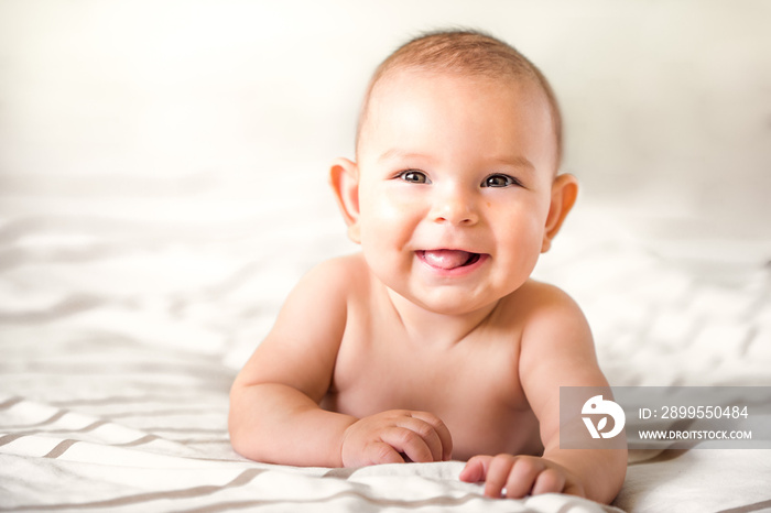 smiling happy newborn infant baby tummy time on bed bright airy copy space childhood