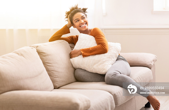 Cheerful Black Girl Sitting On Couch Relaxing At Home