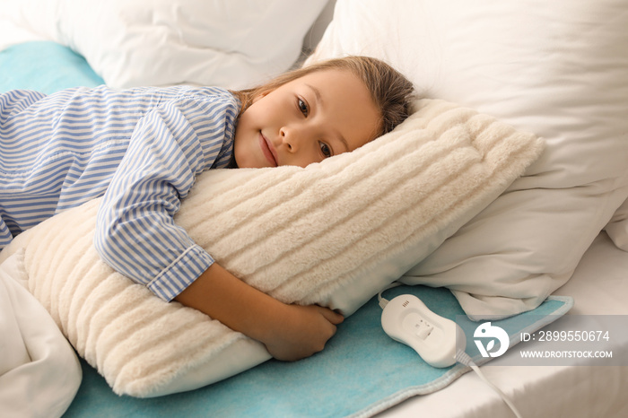 Little girl lying on electric heating pad in bedroom