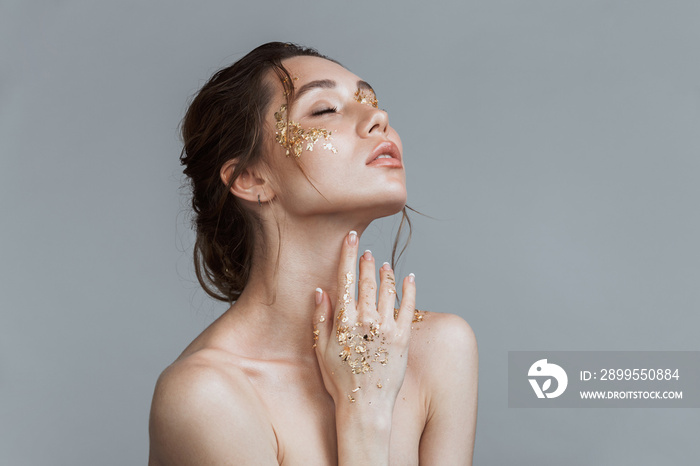 Brunette woman with soft healthy skin and golden makeup