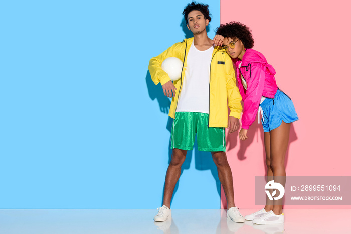 Attractive young couple in sportswear standing against  pink and blue background