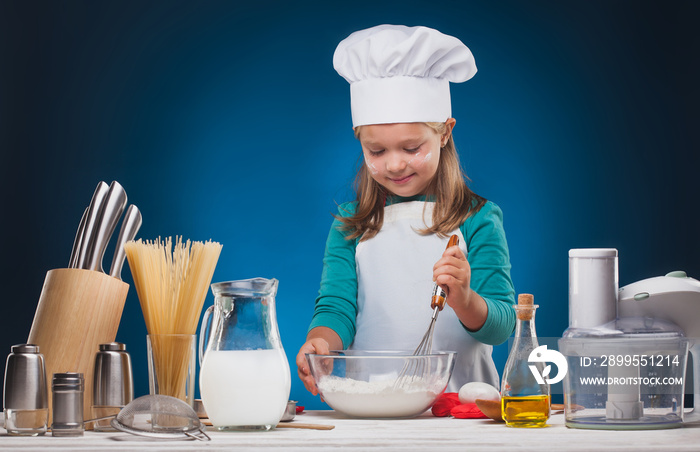 Kid Chef prepares a delicious dish on a blue background.studio portrait