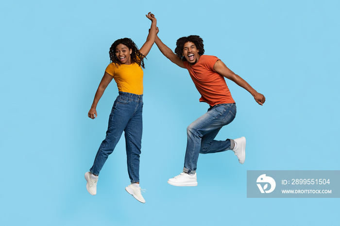 Emotional african american couple celebrating success on blue