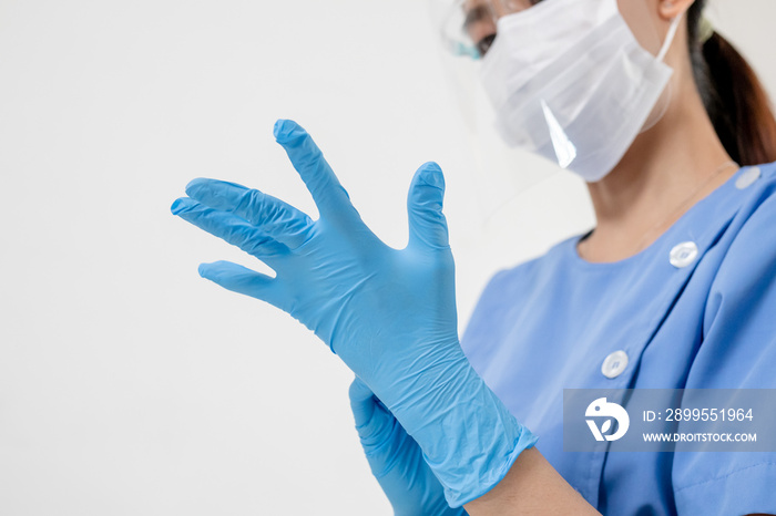 Covid-19,coronavirus hand of young woman doctor or nurse putting on blue nitrile surgical gloves, professional medical safety. Vaccination, immunization or disease prevention against flu concept.