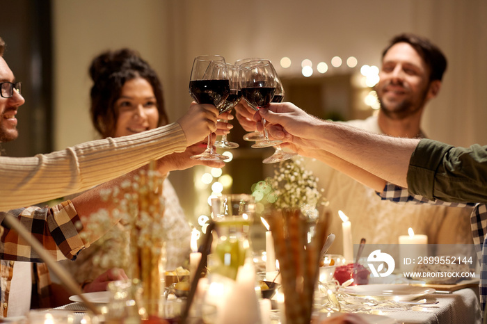 holidays, celebration and people concept - happy friends having christmas dinner at home drinking non-alcoholic red wine