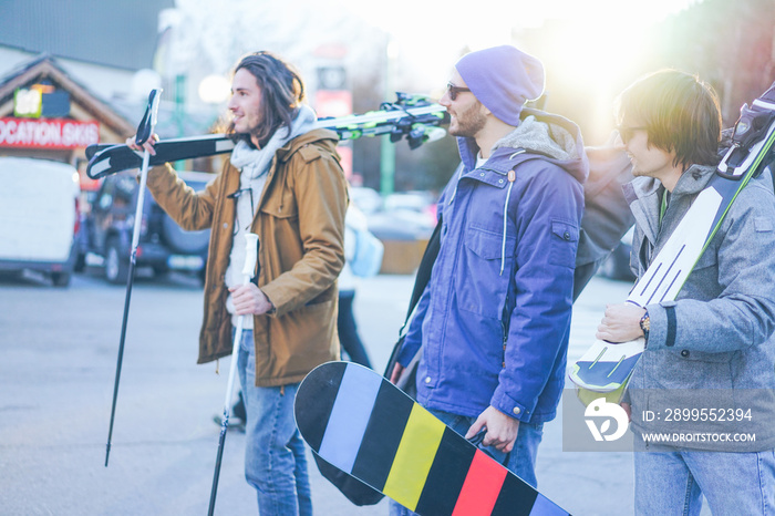 Happy friends going to ski in winter vacation - Young people having fun doing extreme sport at sunrise - Friendship and holidays concept - Focus on left man face - Warm filter