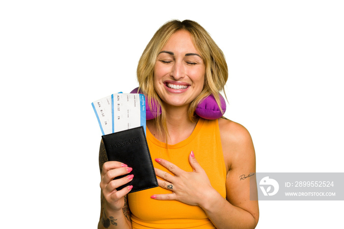 Young caucasian woman with inflatable travel pillow holding passport isolated on green chroma background laughs out loudly keeping hand on chest.