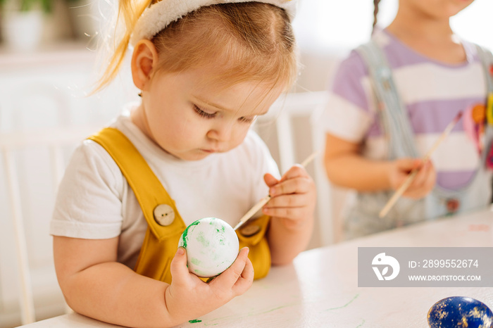 Two happy children draw Easter eggs in a snow-white kitchen. Close-up. the concept of happiness, easter holiday for children