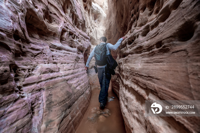 Man hiking through a narrow slot canyon in the Valley of Fire, near Las Vegas, Nevada, USA.