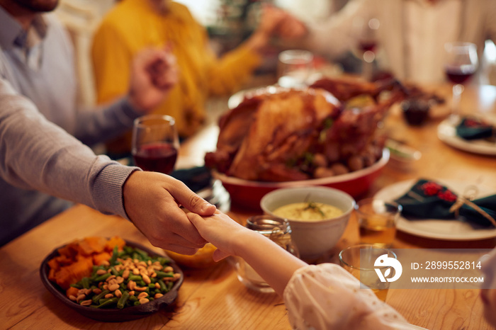 Close-up of father and daughter pray during family meal on Thanksgiving at dining table.