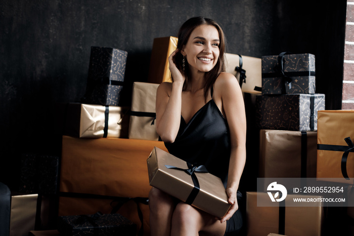 Young happy laughing woman in black dress with gifts