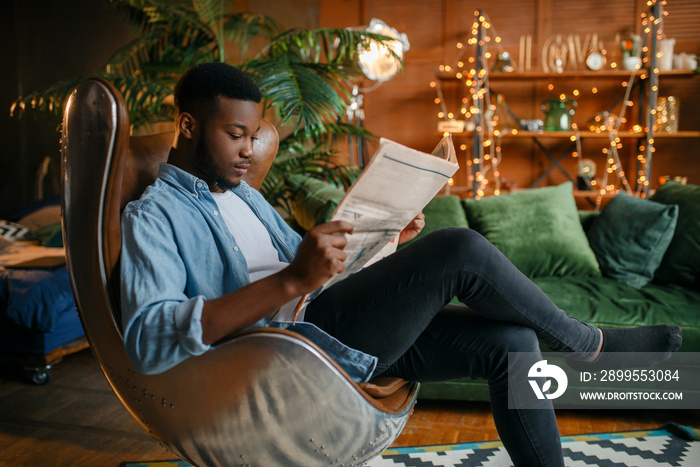 Black man reading newspaper in a comfortable chair