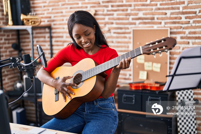 Young african american woman musician playing spanish guitar at music studio