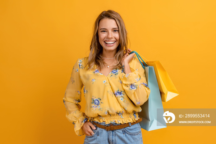 beautiful attractive smiling woman in yellow shirt and jeans holding shopping bags