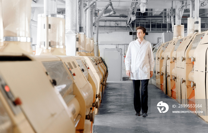 Operator checks operation of automatic modern mill for production of flour from wheat and cereals