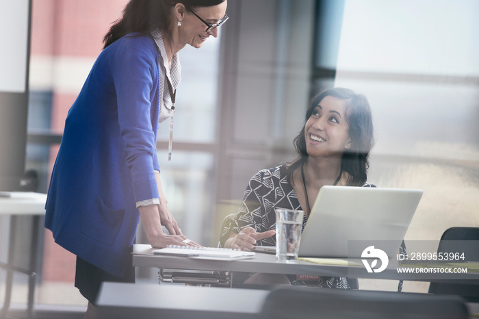 View through glass of two stylish businesswomen having a conversation.