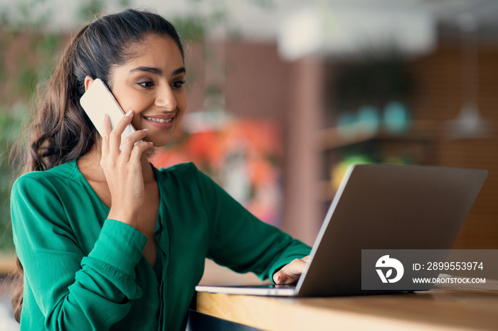 Successful arabic woman working online, having phone conversation, copy space