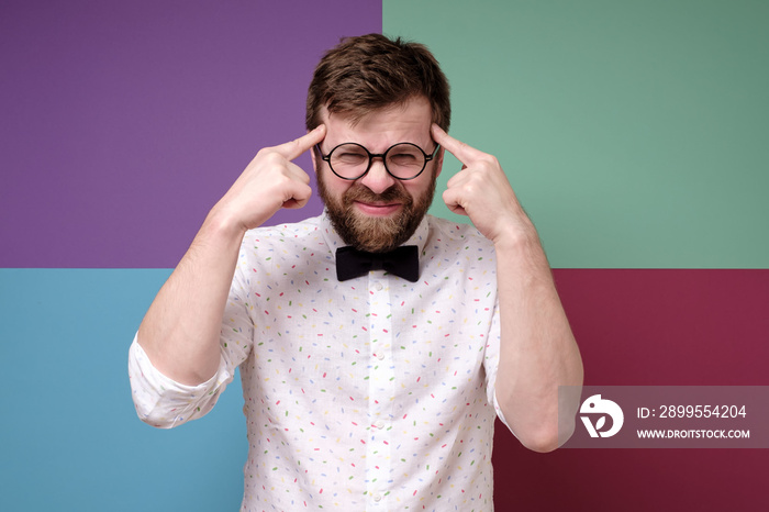 Bearded man in round glasses is trying to remember something, he is trying very hard to gather his thoughts.