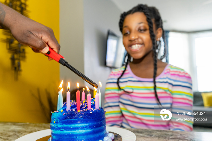 Father and daughter celebrating birthday with blue birthday cake