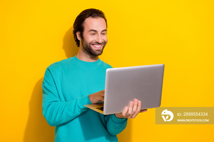 Photo of addicted programmer young student guy hold his computer netbook video conference with colleagues isolated on yellow color background