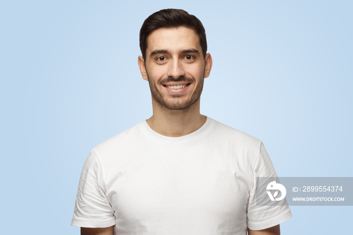 Young smiling attractive man in t-shirt standing isolated on light blue background