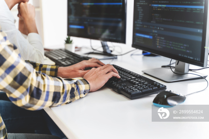 programmer writing program code with two monitors and working on a new software or hacker programming developing software applications in the office.