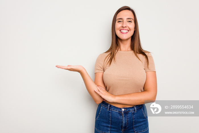 Young caucasian cute woman isolated on white background showing a copy space on a palm and holding another hand on waist.