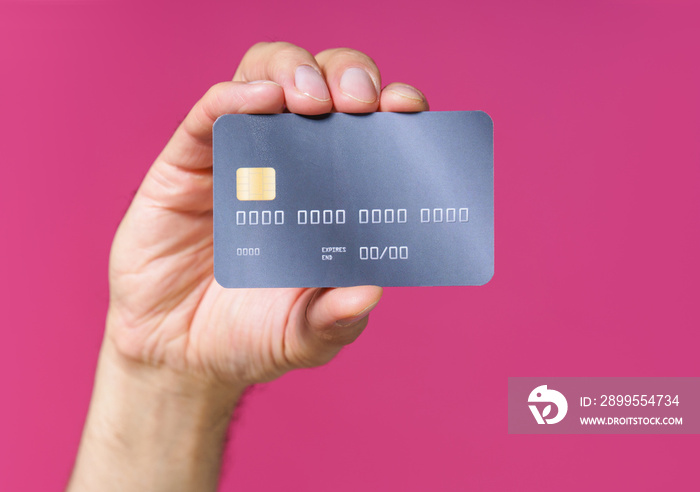 Best offer, dark grey-purple debit, credit card in man hand isolated on pink background. Financial, banking concept. No face visible