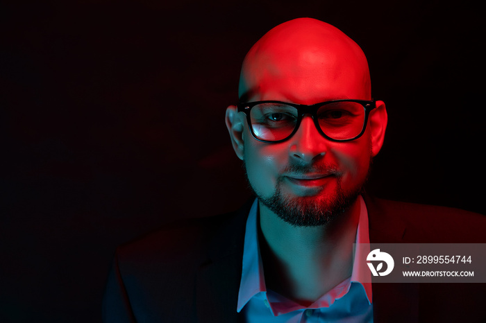 Smiling bald attractive man in suit on neon light background