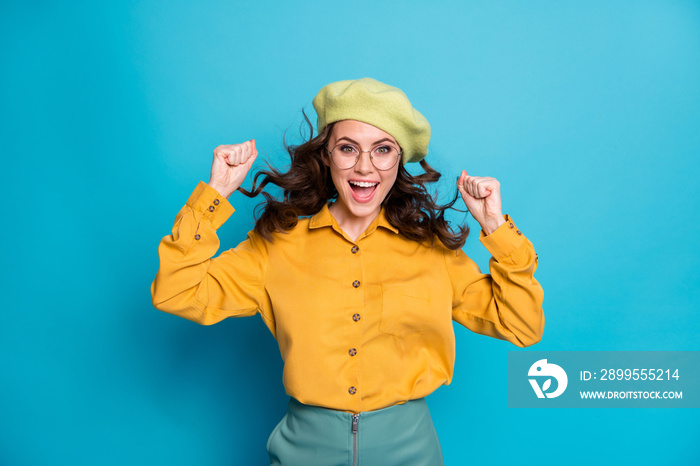 Portrait of excited crazy girl feel ecstatic win lottery raise fists scream yeah haircut air fly blow wear yellow outfit isolated over blue color background