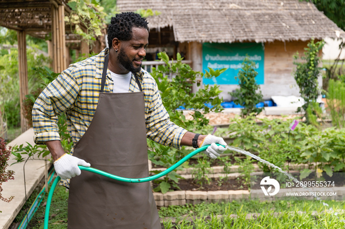 Male farmer watering with hose at agriculture farm